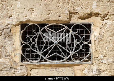 Die dekorative Metall Lüftung grill in Form von 8-zackige Malteserkreuz in eine Steinmauer. Rabat. Malta Stockfoto