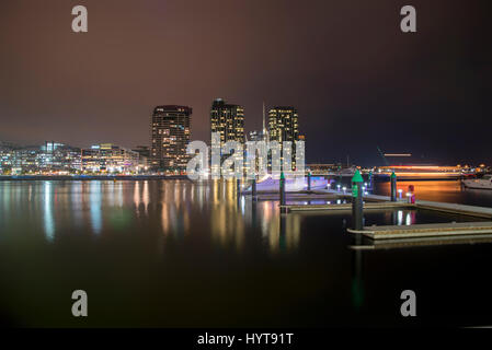 Ein schöner Blick auf eine Stadt am Meer mit bunten Lichtern und Marina mit Privatbooten verankert in der Nacht. Stockfoto