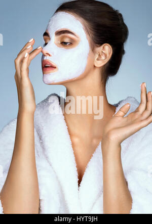 Junge Frau mit feuchtigkeitsspendenden Gesichtsmaske. Foto von einem schönen Brünette ihre Nase zu berühren. Haut-Pflege-Konzept Stockfoto
