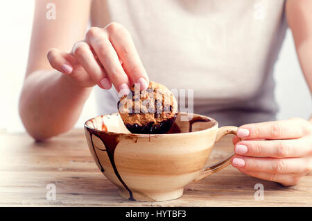 Die Hand der Frau Cookie in die geschmolzene Schokolade eintauchen. Stockfoto