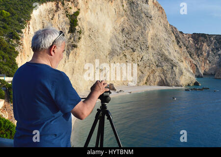 Mann nimmt bei Sonnenuntergang mit seiner Kamera auf Stativ video Katsiki Beach, Griechenland Stockfoto