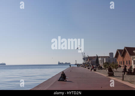 THESSALONIKI, Griechenland - 25. Dezember 2015: Menschen entspannt auf dem Kai - Pier von den alten Hafen von Thessaloniki, eine griechische Flagge zu sehen in der staatlich Stockfoto