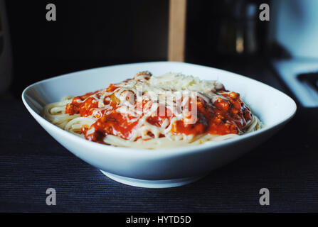 Leckere Spaghetti Bolognese mit Oliven und Mozzarella-Käse auf dunklem Hintergrund. Stockfoto