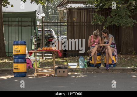 Kiew, UKRAINE - 9. August 2015: Junge Mädchen verkaufen Kwas (ein beliebtes östlichen europäischen Getränk) ist eine Überprüfung ihr Smartphone auf eine Straße Kwas einen traditi Stockfoto