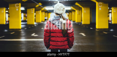 Mädchen mit weißem Hut und rote Jacke stehen im öffentlichen Parkhaus Stockfoto