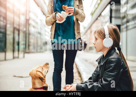 Tochter hören von Musik über Kopfhörer während Mutter und ihr Hund stehen neben Stockfoto