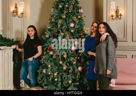 Drei schöne junge Mädchen in der Nähe der Weihnachtsbaum. Horizontale Studioportrait. Stockfoto