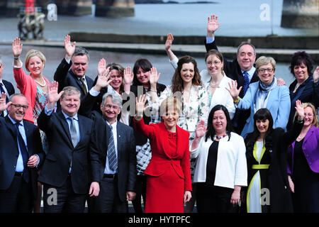 SNP-Führer und schottischen ersten Minister Nicola Sturgeon Wellen zu den Medien und Sujpporters nach eine Rede in South Queensferry, mit ehemaligen Führer Alex Salmond (oben rechts) im Hintergrund Stockfoto