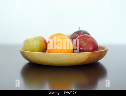 Rote Äpfel und Zitrusfrüchte Orangen auf Holzplatte Stockfoto