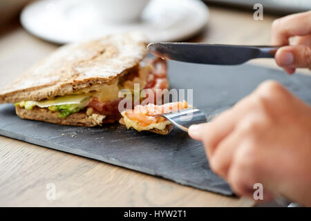 Person essen Lachs Panini Sandwich Restaurant Stockfoto