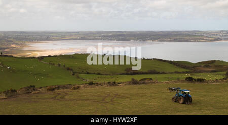 Bauern bei der Feldarbeit über Red Wharf Bay, Anglesey, UK Stockfoto