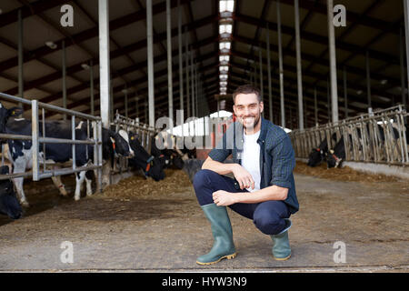 Mann oder Bauer mit Kühen im Stall auf Milchviehbetrieb Stockfoto