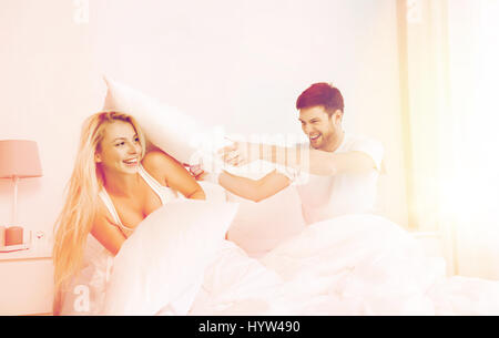 Brautpaar mit Kissen im Bett zu Hause zu kämpfen Stockfoto