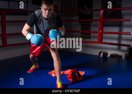 Sportliche männliche Boxer Boxhandschuhe erhebt sich und bereitet sich für den Kampf in regelmäßigen Boxring in ein Fitness-Studio Stockfoto