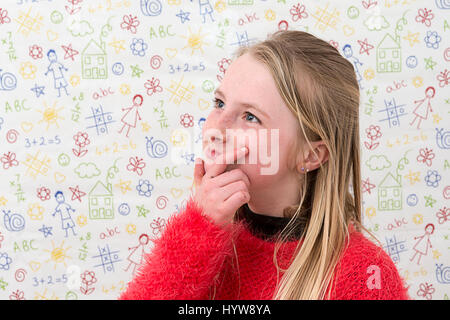 Junge blondes Mädchen rechts von ihr sieht und denkt über ein Problem mit ihren Händen auf ihrem Kinn vor einem Doodle-Hintergrund Stockfoto