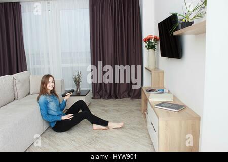 Junge Frau sitzt sitzt auf dem Boden beobachten Fernseher. Stockfoto