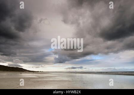 Moody, stürmisch und grauem Himmel drohend über nassen Sand bei Ebbe an einem leeren Strand am Saltburn in North Yorkshire Stockfoto