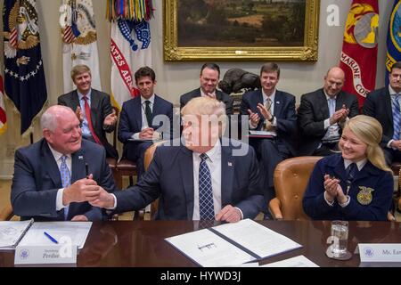 Washington, USA. 25. April 2017. US-Präsident Donald Trump übergibt den Stift Landwirtschaftsminister Sonny Perdue, links, nach der Anmeldung eine Ausführungsverordnung, die Förderung der Landwirtschaft und des ländlichen Raums Wohlstand in Amerika während ein Bauern-Roundtable im Roosevelt Room des weißen Hauses 25. April 2017 in Washington, D.C. Credit: Planetpix/Alamy Live News Stockfoto