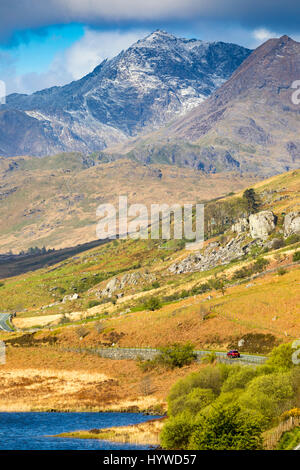 Großbritannien Wetter trocken und klarer über Snowdonia National Park und Mt Snowdon in Nordwales mit einem Auto Anfang auf der A4086 Straße in den Schatten gestellt durch die schiere Größe des Berges Snowdon mit Resten der Schnee des Peaks Stockfoto