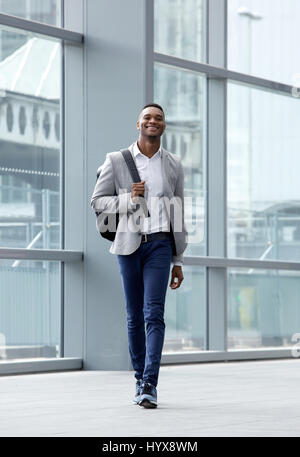 In voller Länge Portrait von ein hübscher junger Mann zu Fuß am Bahnhof mit Tasche Stockfoto