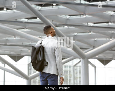 Porträt von hinten von einem schwarzen Mann allein im Flughafen mit Tasche Stockfoto