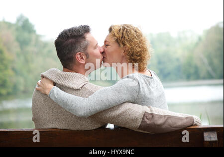 Porträt von einem glücklichen Paar küssen auf Parkbank Stockfoto