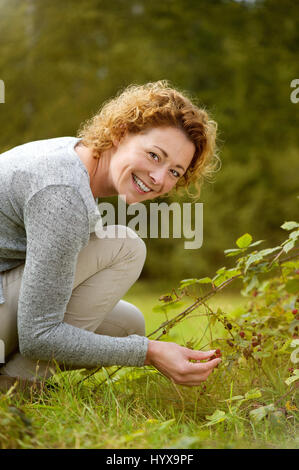Porträt einer lächelnden Frau Beerensammeln im Wald Stockfoto