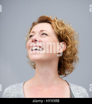 Porträt einer fröhlichen Frau lachend auf grauem Hintergrund hautnah Stockfoto