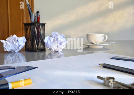 Konzeptsuche für Ideen im Geschäft. Leeres Blatt auf grauen Bürotisch mit zerknitterten Blätter, Kaffee, Regel und Kompass im Hintergrund. Ansicht von vorne. H Stockfoto