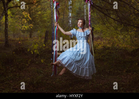 Mädchen auf einer Schaukel in den Wäldern, Vintage retro Kleid schwingen. Stockfoto