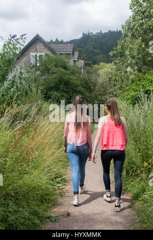 Zwei Mädchen im Teenageralter Fuß entlang der Landstraße mit Hütte im Hintergrund Stockfoto