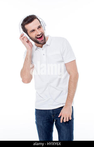 Begeistert junge Mann anhören von Musik im Kopfhörer auf weiß Stockfoto