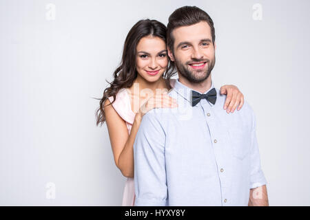 Wunderschöne junge Frau, Mann von hinten umarmt und lächelt in die Kamera Stockfoto