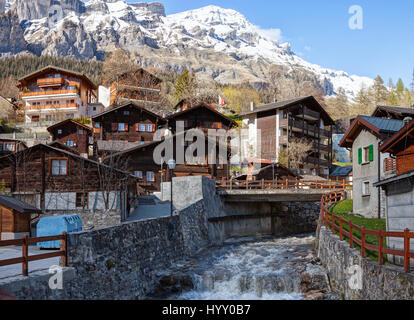 Typische Schweizer Häuser entlang des Flusses Dala an einem Frühlingstag in Leukerbad, Wallis, Schweiz. Stockfoto