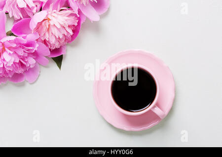 Tasse Kaffee und Blumen (Pfingstrosen) auf grauen Leuchttisch. Stockfoto