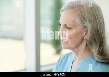 Ältere Frau, die durch Fenster. Stockfoto