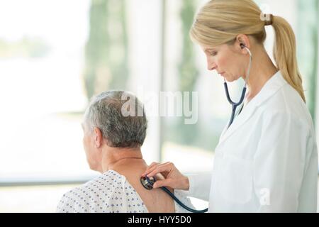 Ärztin mit Stethoskop auf männliche Patienten. Stockfoto