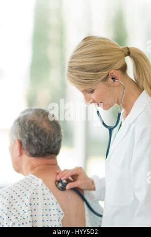 Ärztin mit Stethoskop auf männliche Patienten. Stockfoto