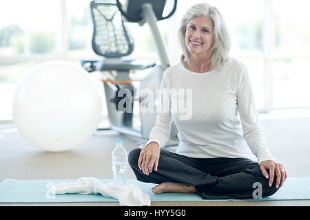 Ältere Frau Schneidersitz sitzen im Fitness-Studio. Stockfoto