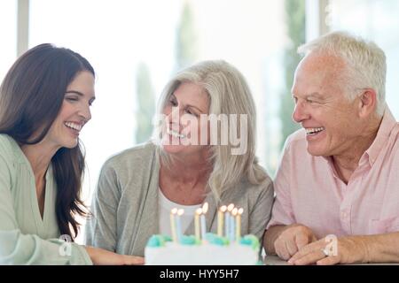 Älteres Paar und Erwachsene Tochter mit Geburtstagstorte. Stockfoto