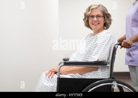 Krankenschwester drängen Patientin im Rollstuhl. Stockfoto