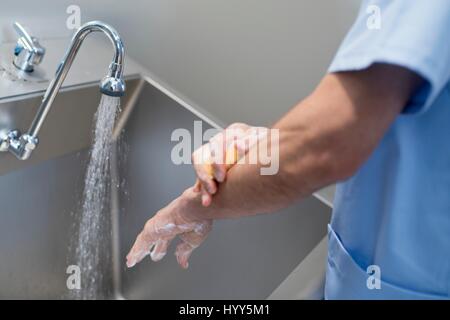 Arzt, Reinigung der Hände mit Seife und Wasser im Krankenhaus. Stockfoto