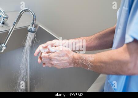 Arzt, Reinigung der Hände mit Seife und Wasser im Krankenhaus. Stockfoto