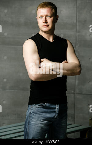 ernster Mann auf dem Hintergrund der Wände aus Beton und Metall-Rohre in ein schwarzes Hemd Stockfoto