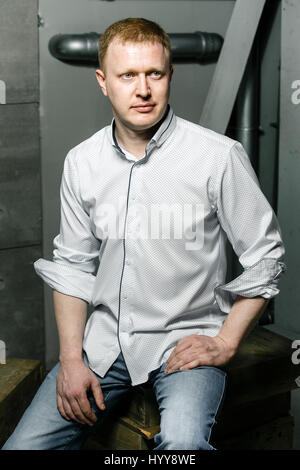ernster Mann auf dem Hintergrund der Wände aus Beton und Metall-Rohre in ein schwarzes Hemd Stockfoto