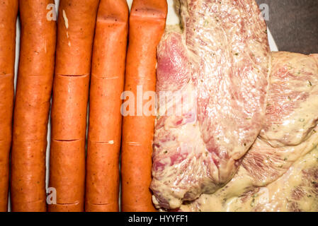 weißer Teller mit Fleisch zum Grillen grillen Würstchen Steak roh bereit für Feuer hautnah Stockfoto