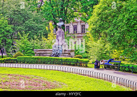 Krakau, Polen - 1. Mai 2014: Artur Grottger Statue im Stadtpark Planty in Krakau, Polen. Person, die entspannend auf die Bank. Stockfoto