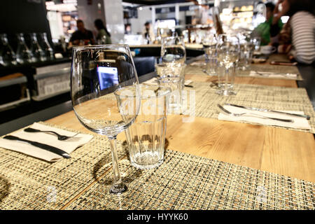 Leere Gläser werden auf eine Bar in einem Restaurant, Menschen im Hintergrund eingerichtet. Stockfoto