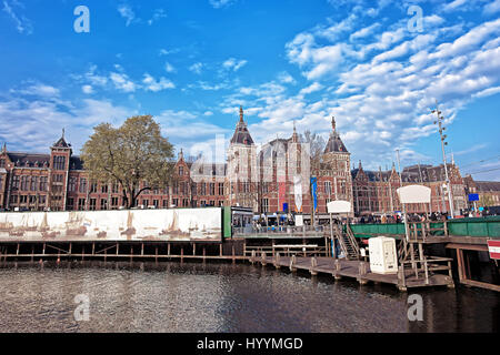 Amsterdam, Niederlande - 3. Mai 2013: Kanal am offenen Havenfront in Amsterdam, Niederlande. Centraal Bahnhof und Menschen auf dem Hintergrund Stockfoto