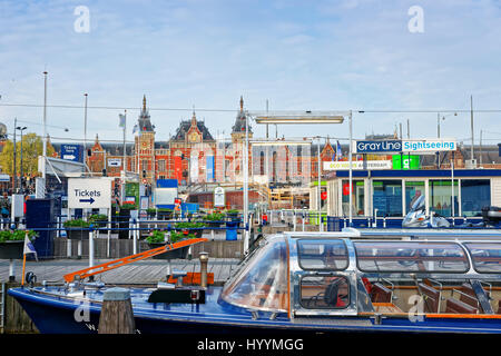 Amsterdam, Niederlande - 3. Mai 2013: Kanalboote auf offenen Havenfront in Amsterdam, Niederlande. Hauptbahnhof auf dem Hintergrund Stockfoto